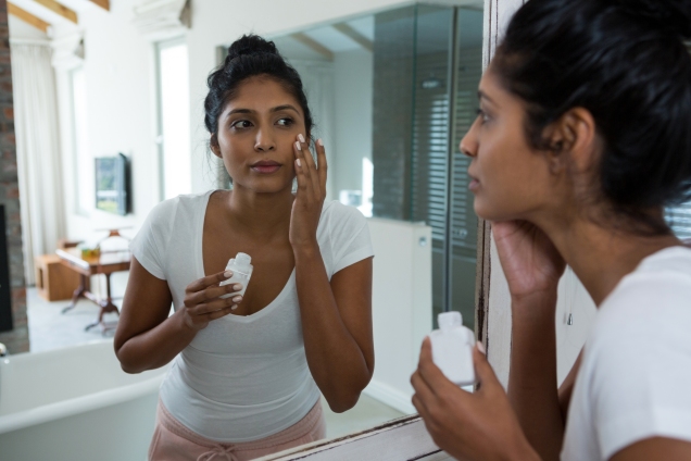 Woman applying moisturizer at home